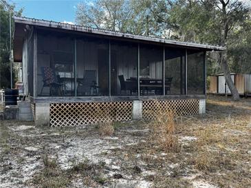 Rustic cabin with screened porch, mature trees, and peaceful surroundings at 15215 Se 255Th Ave, Umatilla, FL 32784