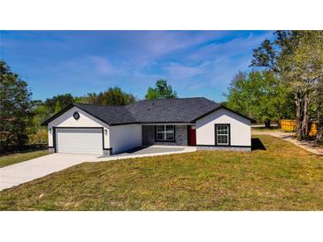 Charming single-story home featuring a modern design, well-maintained lawn, and paved driveway at 19 Juniper Pass, Ocala, FL 34480
