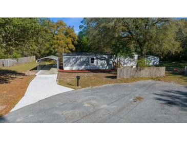 Charming home features a gray exterior with a carport and well-maintained landscaping at 221 Se 167Th Ct, Silver Springs, FL 34488