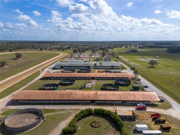 Expansive horse farm showcasing multiple barns, paddocks, training areas, and a racetrack against a scenic landscape at 4695 Ne 112Th Ln, Anthony, FL 32617