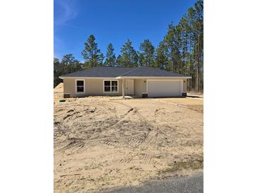 New construction home featuring neutral colors, an attached garage, and front yard surrounded by tall trees at 1370 Sw Obee Ridge Rd, Dunnellon, FL 34432