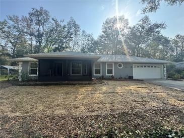 Charming single-story home with a screened-in porch, lush trees, and well-maintained landscaping at 13949 Se 53Rd Ave, Summerfield, FL 34491