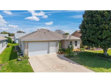 Charming single-story home with a well-manicured lawn, decorative driveway, and a two-car garage on a sunny day at 17959 Se 89Th Natchez Ave, The Villages, FL 32162