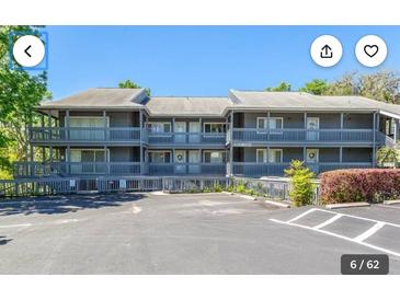 Three-story condominium building with balconies and ample parking on a sunny day at 20800 River Dr # A17, Dunnellon, FL 34431