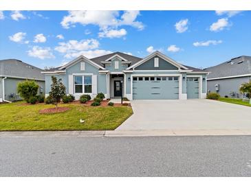 Charming one-story home with a well-manicured lawn and beautiful blue and gray color palette at 4384 Pezzullo Cir, The Villages, FL 32163