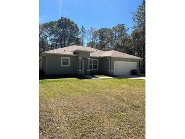 Charming single story home featuring a well-maintained lawn, attached garage, and welcoming entrance at 6884 Sw 149Th Lane Rd, Ocala, FL 34473
