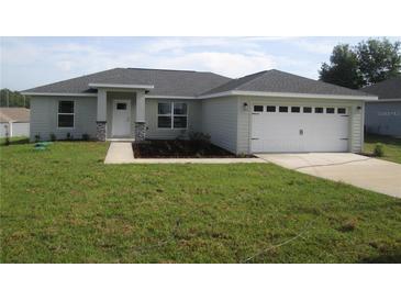 Charming single-story home with a well-manicured lawn, two-car garage, and inviting entrance at 9455 Se 152Nd Pl, Summerfield, FL 34491