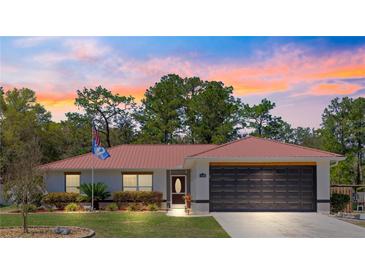 Charming single-story home boasts a metal roof, well-manicured lawn, and a two-car garage at 1192 Ne 130Th Ter, Silver Springs, FL 34488