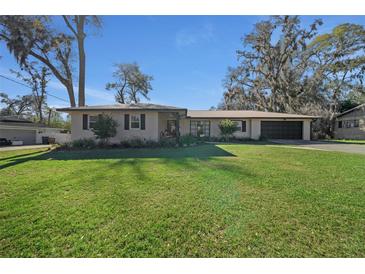 Charming single-story home features a lush green lawn, attached garage, and mature trees at 1732 Se 38Th Ct, Ocala, FL 34471