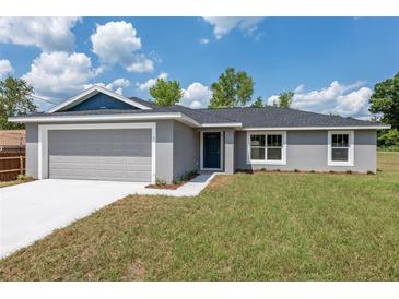 Charming single-story home featuring a gray exterior, a two-car garage, and a well-maintained lawn at 2 Hemlock Ter Dr, Ocala, FL 34472