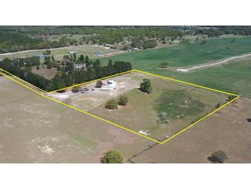 An aerial view of a property with a large open field, treeline, residence, and a yellow boundary line at 2061 Nw 165Th Court Rd, Dunnellon, FL 34432
