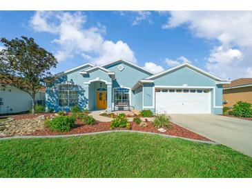 Charming single-story home with a well-manicured lawn, colorful flower beds, and a bright yellow front door at 15092 Sw 14Th Avenue Rd, Ocala, FL 34473