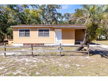 Charming single-story home featuring a rustic wooden fence, inviting entrance, and lush palm tree at 1533 Pine St, Apopka, FL 32703