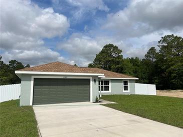 Charming single-story home with a two-car garage, green lawn, and a combination of trees and cloudy blue sky at 2722 Sw 151St Ave, Ocala, FL 34481
