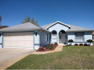 Charming single-story home featuring a well-manicured lawn, two-car garage, and a welcoming front entrance at 7407 Sw 112Th Pl, Ocala, FL 34476