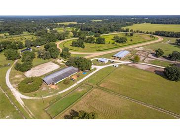 Expansive horse farm with a racetrack, barns, stables, and lush green pastures, providing ample space for equestrian activities at 13800 Ne Jacksonville Road, Citra, FL 32113