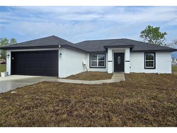 Newly constructed home with a black garage door and trim against a white stucco exterior at 17 Laurel Pass Ln, Ocala, FL 34480
