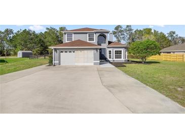 Charming home featuring a two-car garage, manicured lawn, and inviting front entrance at 10910 Sw 47Th Ct, Ocala, FL 34476