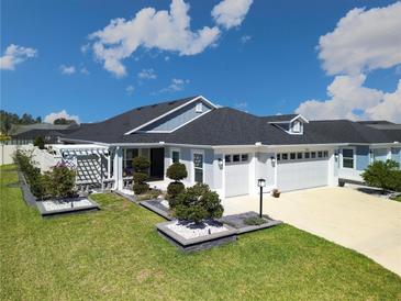 Beautiful single-story home featuring a two-car garage, manicured lawn, and elegant landscaping at 7014 Elaine Ct, The Villages, FL 34762