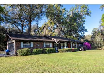 Charming brick home with a well-maintained lawn and mature trees offering shade and curb appeal at 2570 Se Highway 42, Summerfield, FL 34491