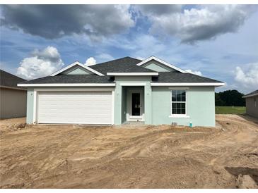 Charming single-story home with a two-car garage, light blue paint, and a well-maintained yard under a cloudy sky at 4504 Sw 90Th Lane Rd, Ocala, FL 34476