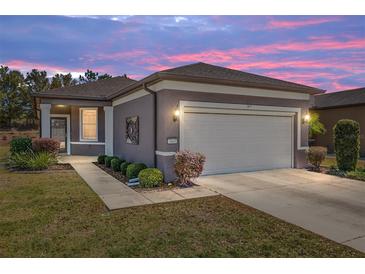 Charming home exterior featuring a two-car garage, manicured landscaping, and a pathway to the front door at 7665 Sw 96Th Avenue Rd, Ocala, FL 34481
