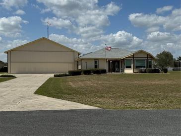 Charming single-story home with attached hangar and well-manicured front lawn at 9700 Se 72Nd Ave, Ocala, FL 34472