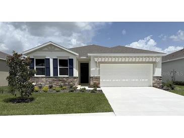 Charming one-story home with stone accents, a manicured lawn, and a two-car garage at 3088 Canopy Oak Blvd, Wildwood, FL 34785