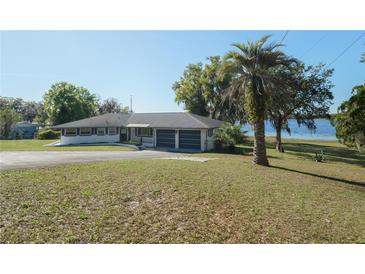 Expansive single story home featuring a two car garage and a large yard with mature trees on a sunny day at 390 Sw Shorewood Dr, Dunnellon, FL 34431