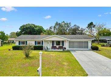 Charming single-story home featuring well-maintained landscaping, a screened garage, and a welcoming front porch at 10190 Se 178Th St, Summerfield, FL 34491