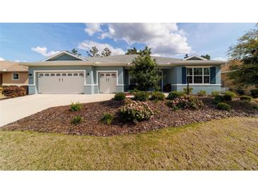 Charming home featuring a well-manicured lawn, beautiful landscaping, and a three-car garage at 10445 Sw 90Th Street Rd, Ocala, FL 34481
