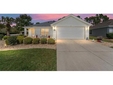Charming home featuring a two-car garage, beautiful landscaping, and a cozy front patio at 11828 Se 91St Cir, Summerfield, FL 34491