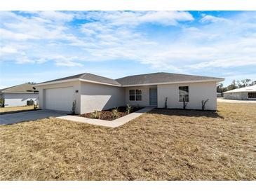 Charming single-story home featuring a clean stucco facade, attached garage, and a neatly maintained front yard at 1698 Ne 161 St, Citra, FL 32113