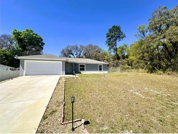 Charming single-story home with a well-maintained lawn and a two-car garage on a sunny day at 416 Marion Oaks Crse, Ocala, FL 34473