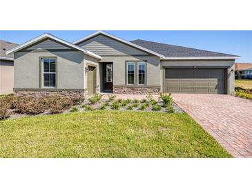 Charming one-story home featuring a stone accent, landscaped yard, and brick driveway leading to an attached garage at 4497 Nw 54Th Ter, Ocala, FL 34482