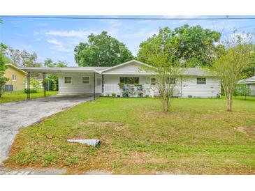 Inviting one-story home featuring a carport, a cozy front porch, and a well-kept lawn at 4516 Ne 8Th St, Ocala, FL 34470