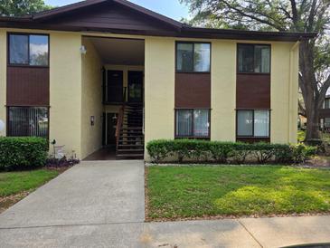 A cream and brown two-story condo building with stairs and a green lawn at 501 Fairways Ln # A, Ocala, FL 34472