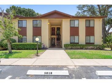 Two-story condo building featuring a beige facade with brown accents, stairs to the second level, and manicured landscaping at 501 Fairways Ln # A, Ocala, FL 34472