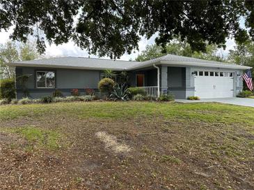 Charming single-story home with a two-car garage, manicured lawn, and colorful flowerbeds at 6082 Sw 104Th St, Ocala, FL 34476