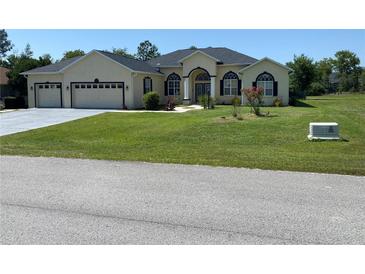 Charming single-story home with a well-manicured lawn and a three-car garage, set against a blue sky at 5323 Sw 111Th Lane Rd, Ocala, FL 34476