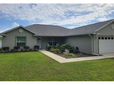 Attractive single-story home featuring a well-kept lawn, landscaped garden, and an attached two-car garage at 9188 Se 150Th St, Summerfield, FL 34491