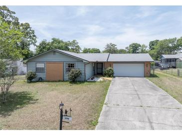 Charming single-story home with a well-manicured lawn and a long driveway leading to an attached garage at 3990 Se 20Th Ct, Ocala, FL 34480