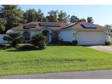 Well maintained single story home featuring solar panels, a lush lawn, and a two car garage at 4413 Sw 145Th Place Rd, Ocala, FL 34473