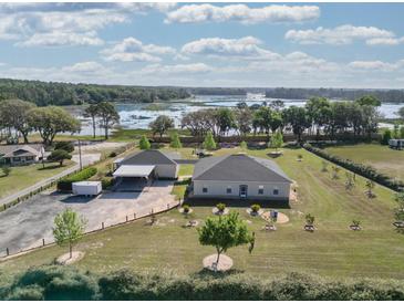 Beautiful aerial view of the property with lush landscaping and a picturesque lake in the background at 11395 Se 108Th Terrace Rd, Belleview, FL 34420