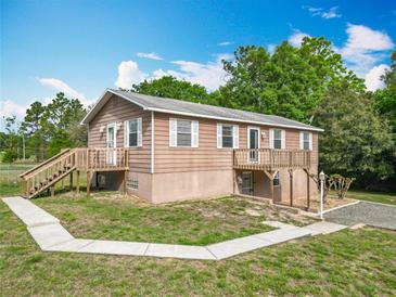 Charming two-story home featuring a wooden deck, walkway, and lovely landscaping against a blue sky at 2800 Sw 141St Ct, Ocala, FL 34481