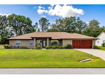 Charming single-story home featuring a manicured lawn and a stylish, wood-look garage door at 5770 Sw 89Th Pl, Ocala, FL 34476