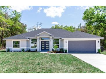 Beautiful home featuring a manicured lawn, gray paint, and a matching garage door at 8878 Sw 133Rd Lane Rd, Ocala, FL 34473