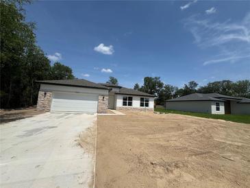 New home with a two-car garage, stone accents, and a spacious front yard ready for landscaping at 11537 Sw 59Th Ter, Ocala, FL 34476