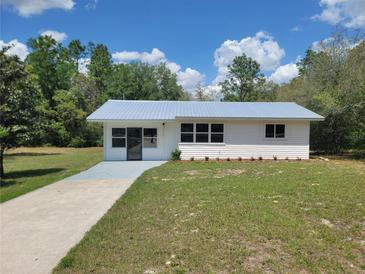 Charming single-story home with a metal roof, tidy lawn, and freshly painted long driveway at 23177 Sw Beach Blvd, Dunnellon, FL 34431