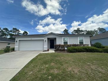 Charming single-story home featuring a well-manicured lawn, gray exterior and a two-car garage at 593 Marion Oaks Trl, Ocala, FL 34473